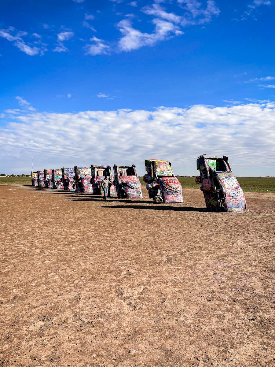 Several cars with graffiti lined up in a row at Cadillac Ranch